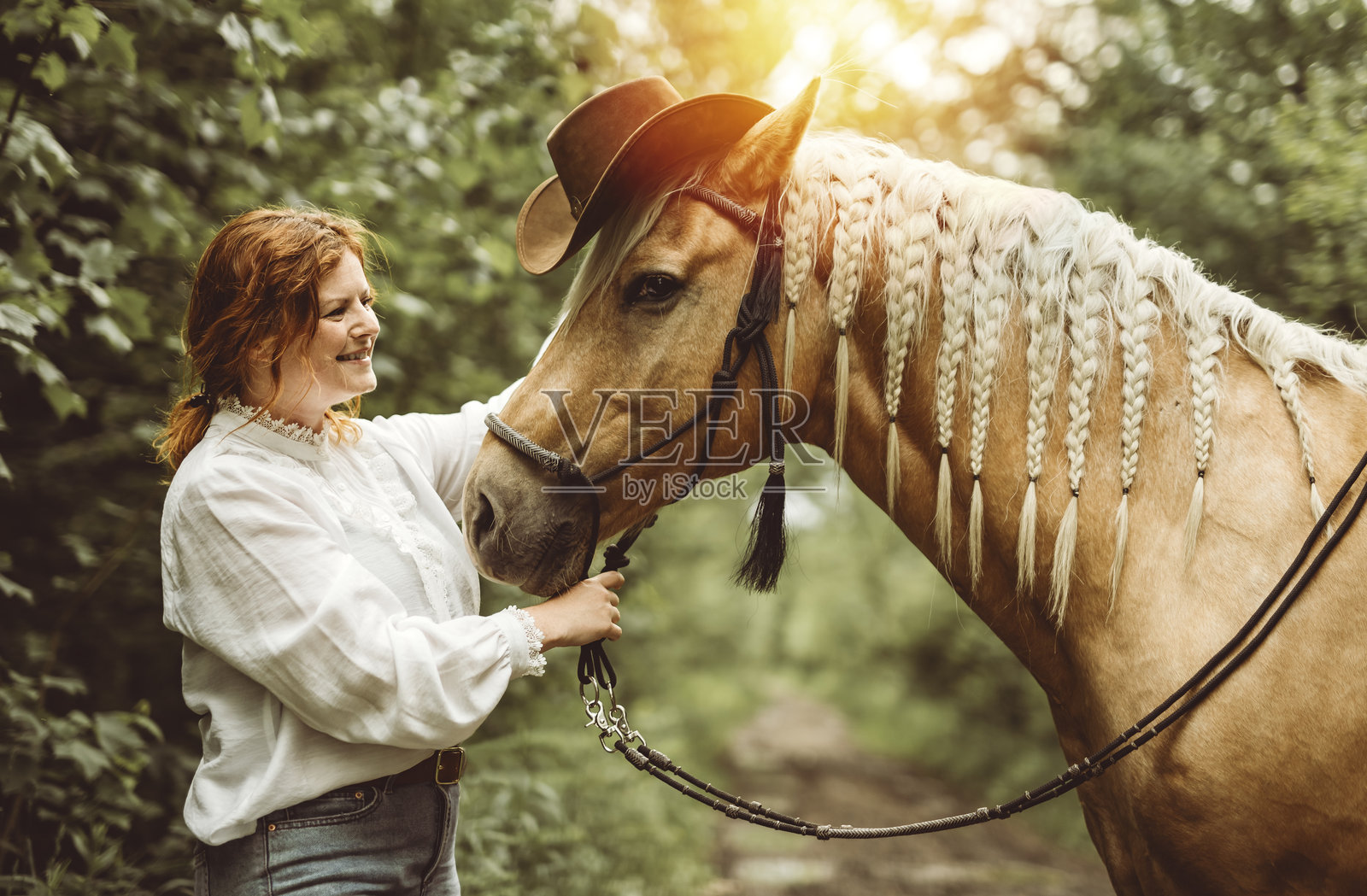 一个女人戴着牛仔帽在开阔的田野上骑马照片摄影图片