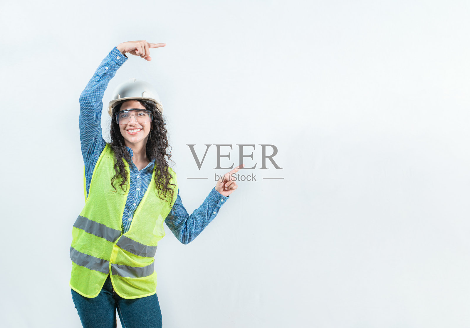 微笑着的女性建筑工人，指着广告，孤立的。美丽的女性工程师用双手指向旁边，孤立的。照片摄影图片