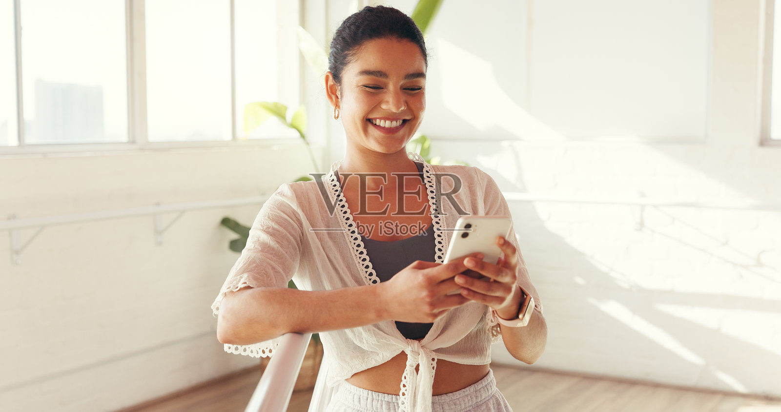 手机、微笑的女性在健身房锻炼，在线追踪健康进度或信息。快乐的人在工作室使用手机查看普拉提、锻炼计划或社交媒体上的健康应用。照片摄影图片