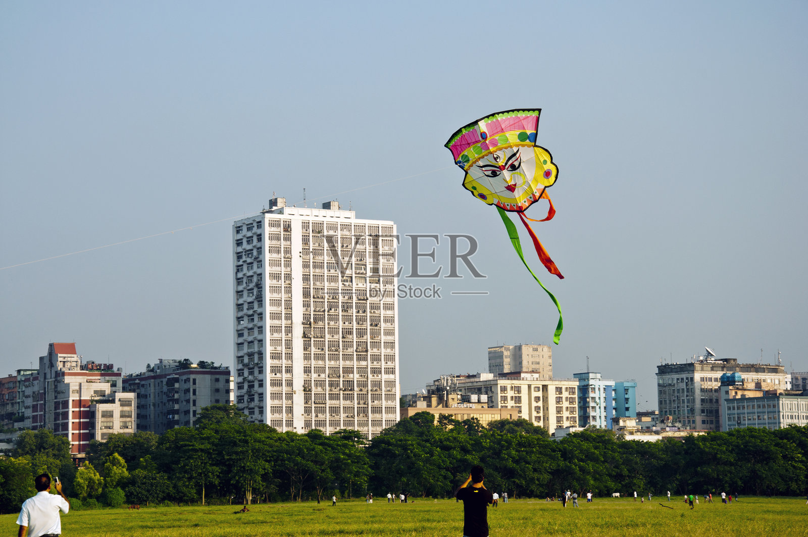 人们在城市空地上享受放风筝的乐趣。照片摄影图片