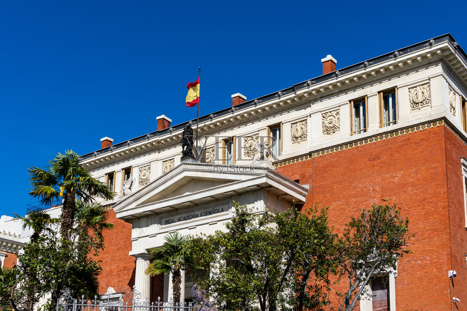 马德里，西班牙皇家语言学院大楼挥舞着西班牙国旗照片摄影图片