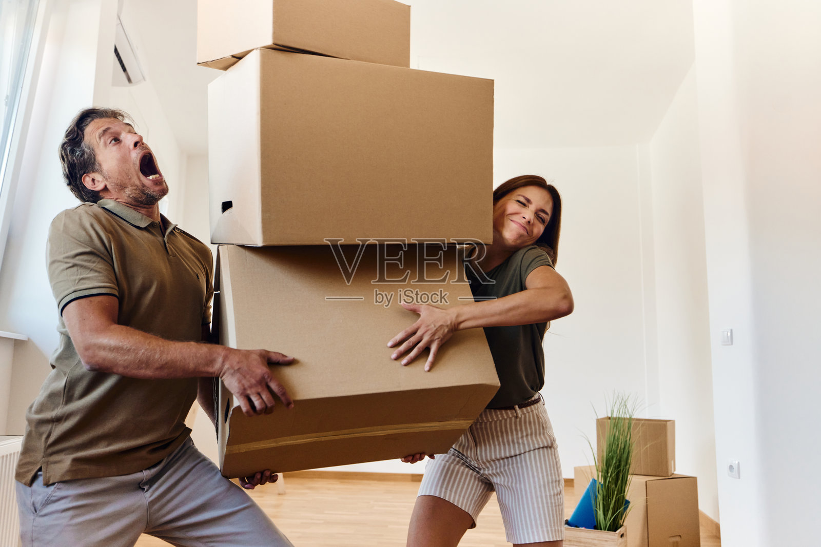搬入新家后，一对情侣正在搬运沉重的箱子。照片摄影图片