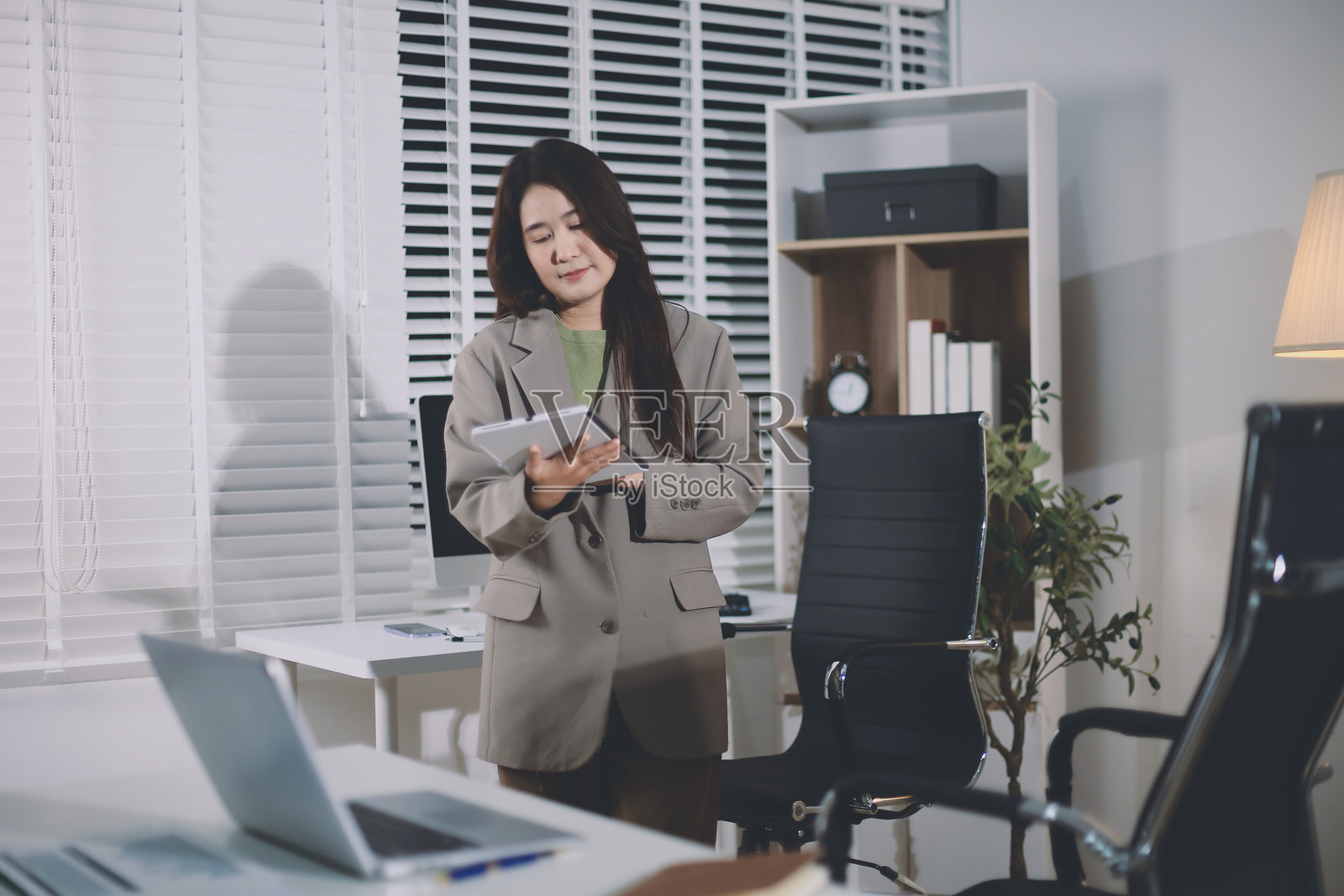 办公室里站着的年轻西班牙裔职业女性肖像。快乐的女公司高管、微笑的女商界领袖、企业家、公司领导者、经理看着镜头，使用平板电脑。照片摄影图片