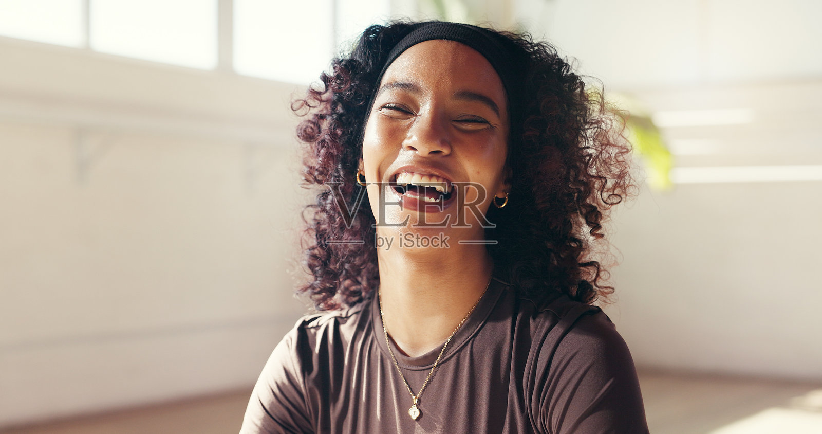 肖像，一位女士在瑜伽课上开怀大笑，享受健身休息和整体运动的趣味笑话。她面带微笑，放松身心，进行禅修练习，以缓解压力，促进普拉提养生中的肌肉恢复。照片摄影图片