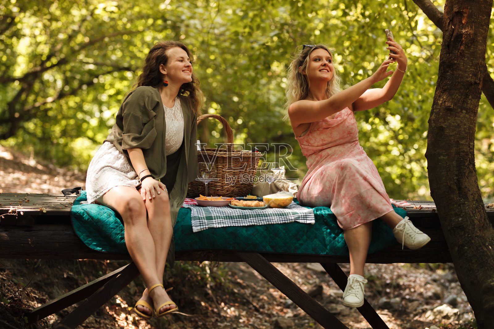 两位朋友在阳光明媚的下午，于宁静的森林中共享野餐，并一起自拍。照片摄影图片