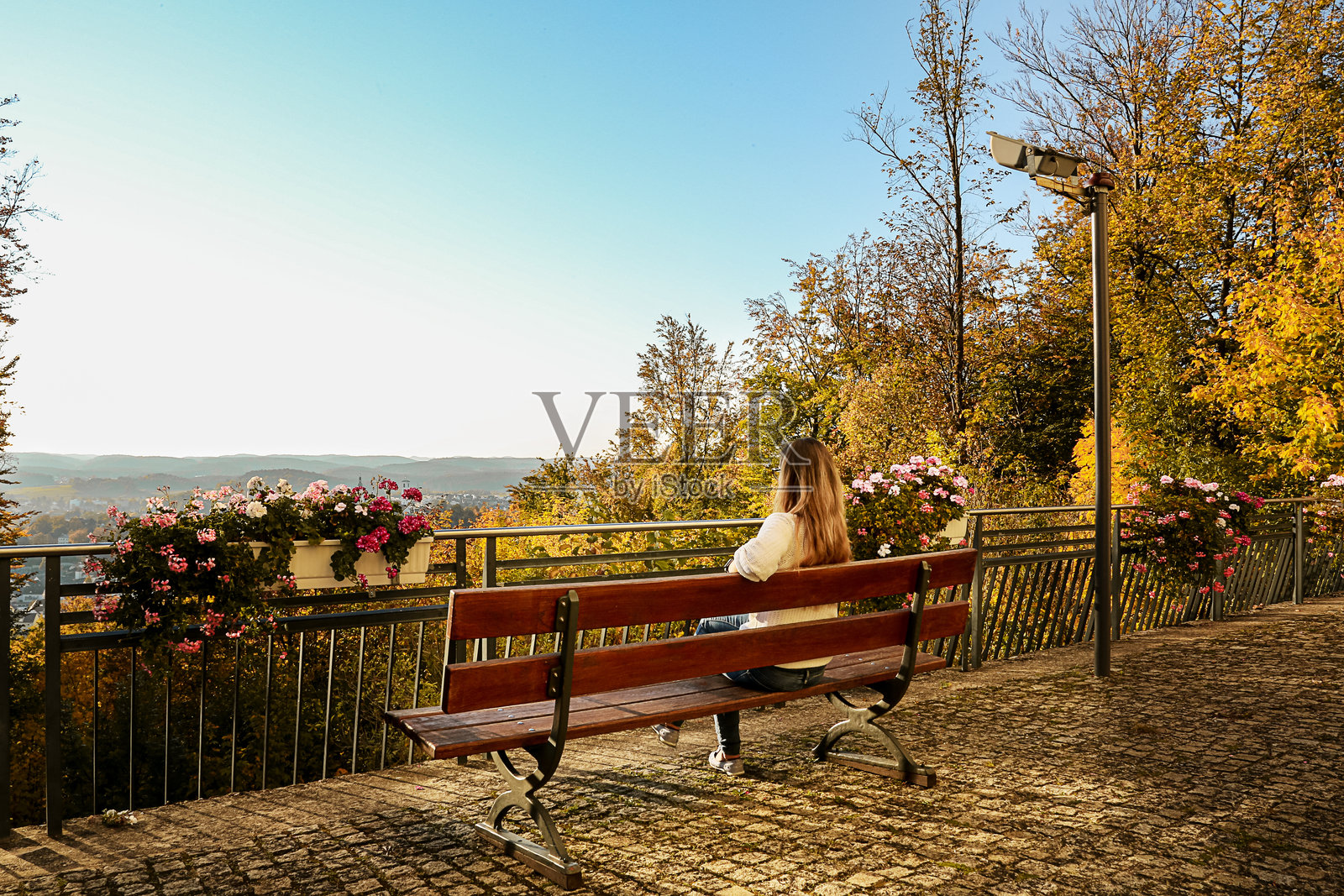一位女士坐在长椅上，欣赏秋日美景照片摄影图片