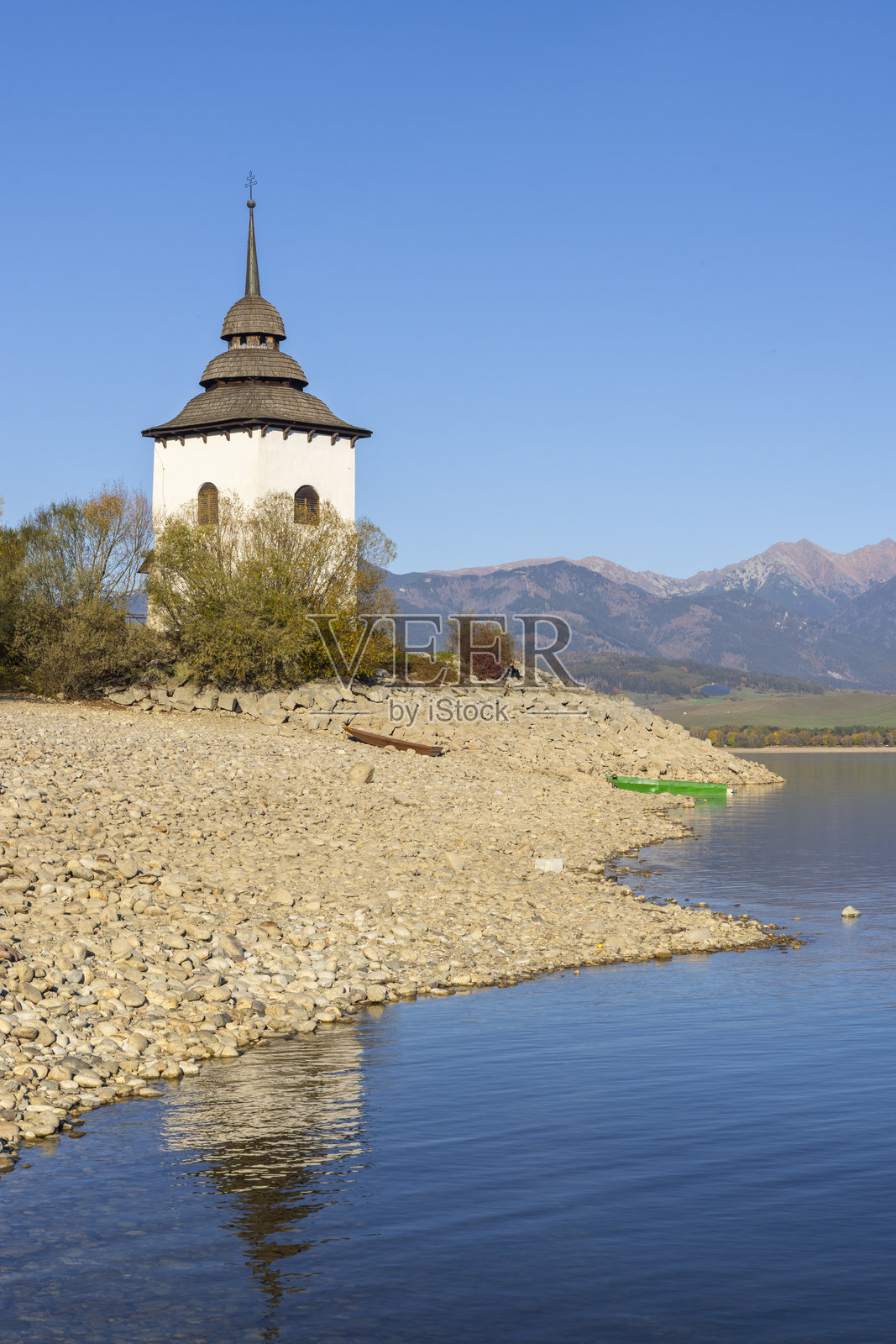 背景为西部塔特拉山，利普托夫斯卡马拉水库和被淹没村庄的教堂塔楼。照片摄影图片