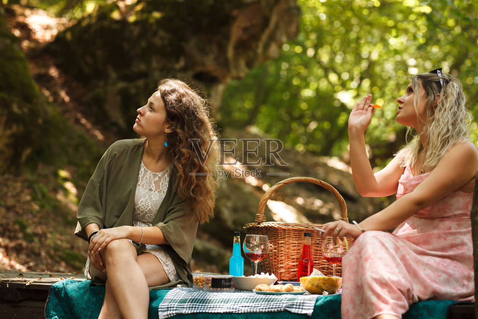 两个朋友在宁静的森林里享受野餐，在温暖的阳光下分享故事和美食，四周绿意盎然。照片摄影图片