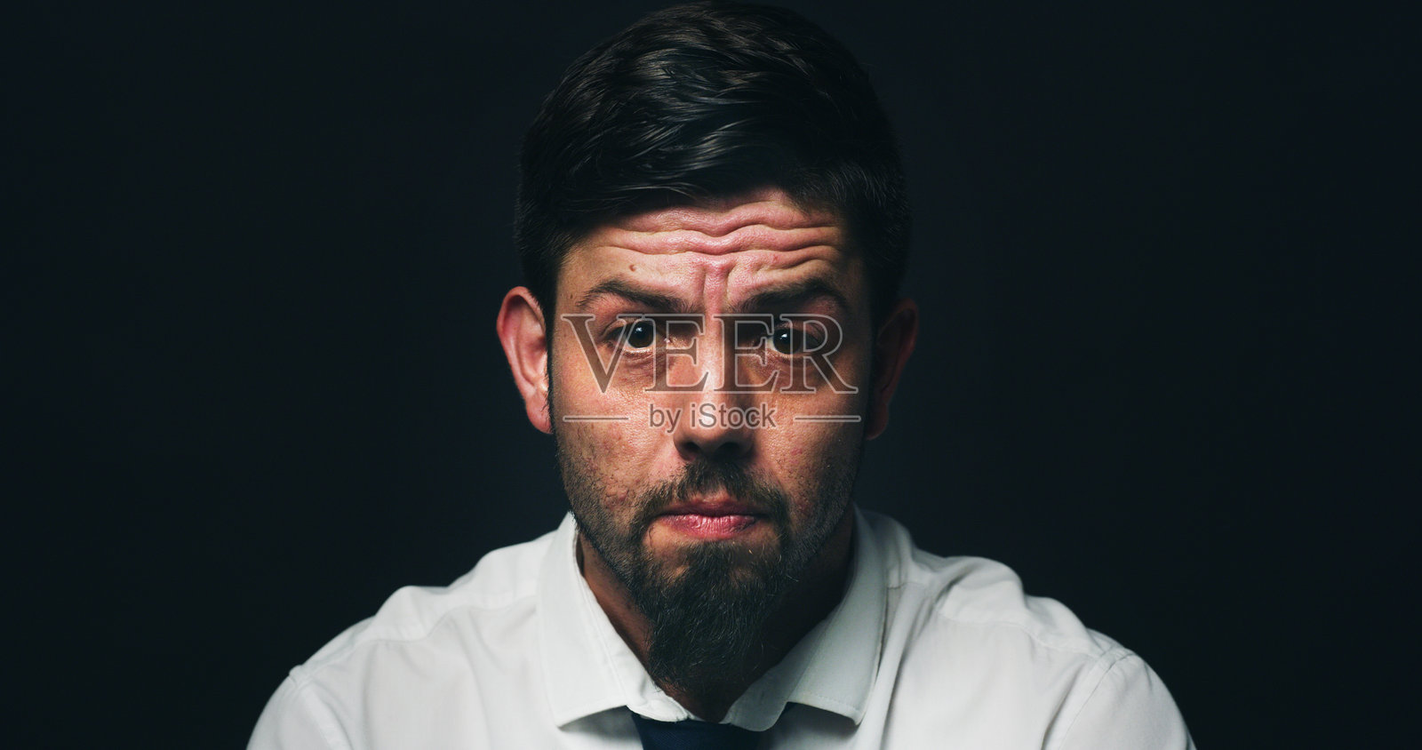 商人肖像，在工作室里因金融危机和破产而显得沮丧、抑郁，背景为黑色，留有空间。这个人愁眉苦脸，因心理健康、焦虑或愤怒而感到沮丧。照片摄影图片