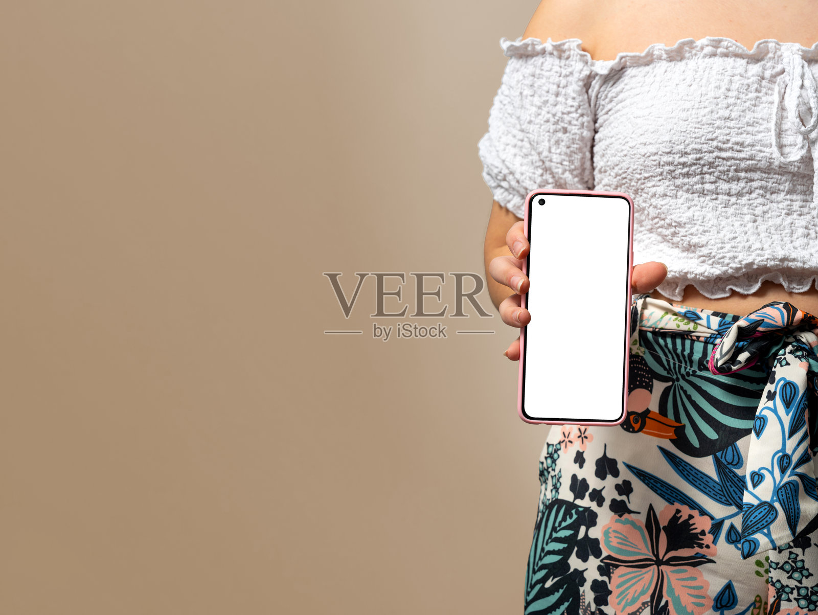 一名女子手持带有空白白色屏幕的粉色智能手机模型照片摄影图片