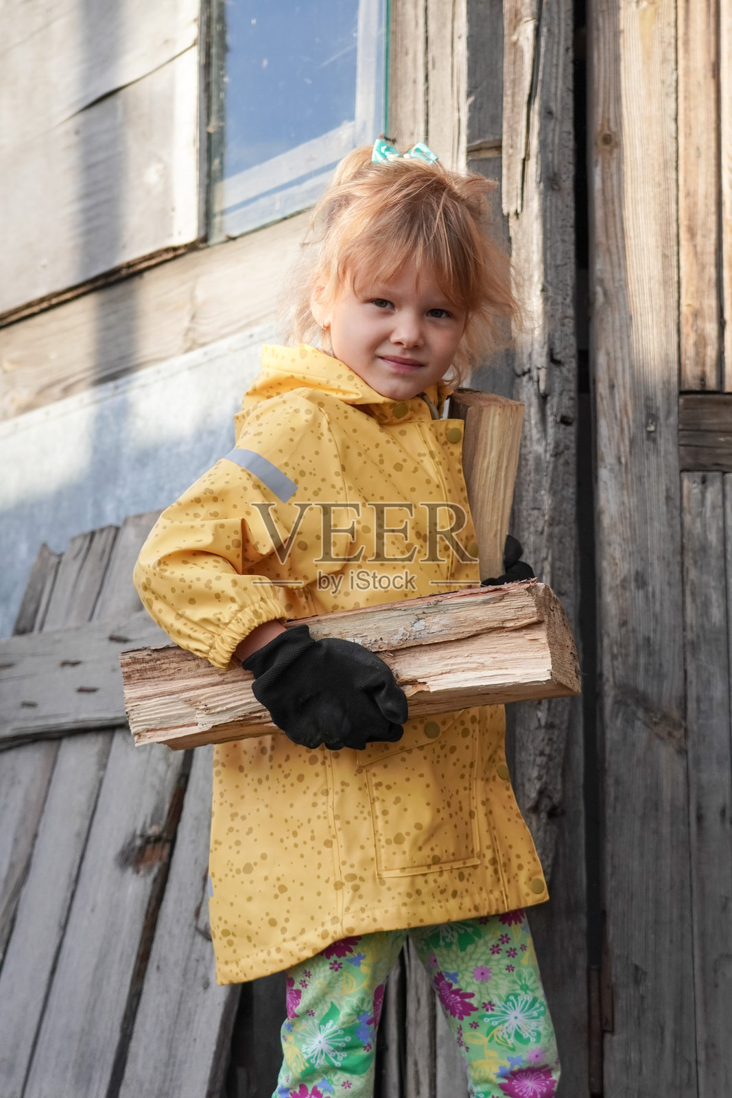 一个微笑着的孩子在户外抱着柴火照片摄影图片