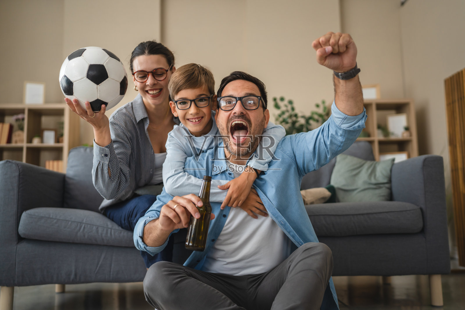 一家人一起在家观看足球比赛时的欢呼场景照片摄影图片