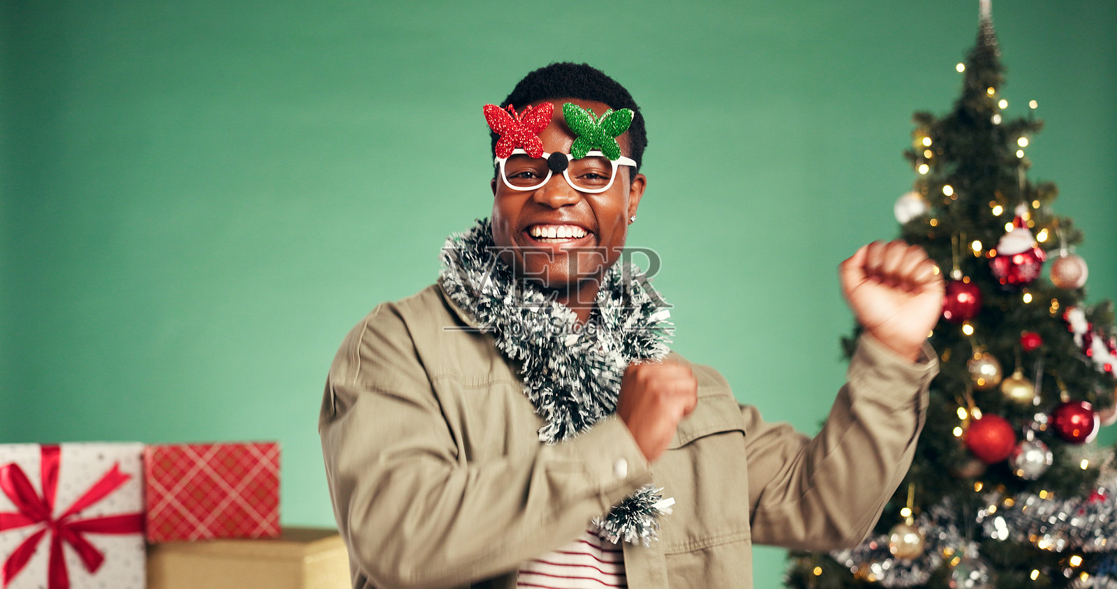 肖像，一名黑人男子在演播室为圣诞假期、圣诞派对和庆祝活动跳舞。微笑，人物和音乐用于表演，节奏和能量用于节日绿色背景。照片摄影图片