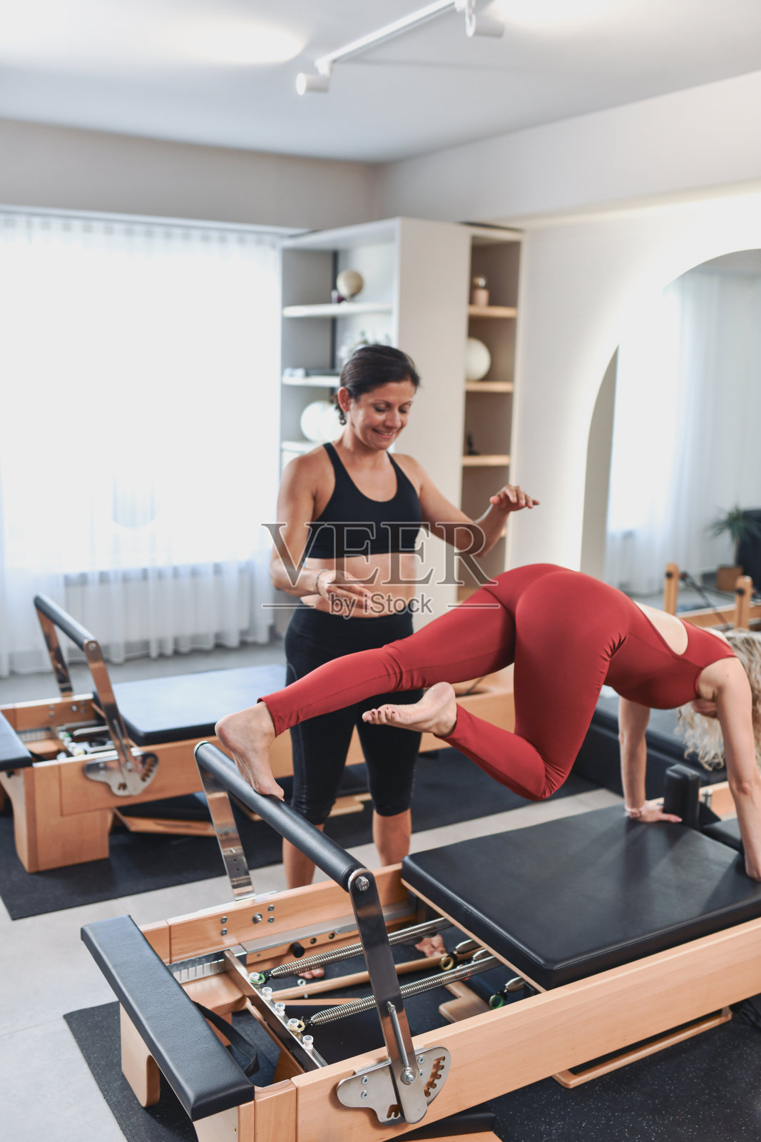 专业教练指导女性进行普拉提器械训练照片摄影图片