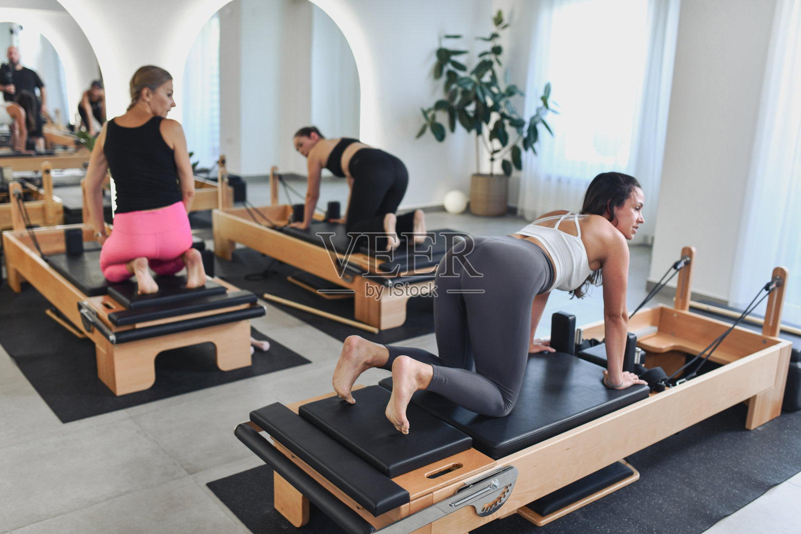 明亮工作室里，女性运动员正在练习普拉提器械伸展运动照片摄影图片