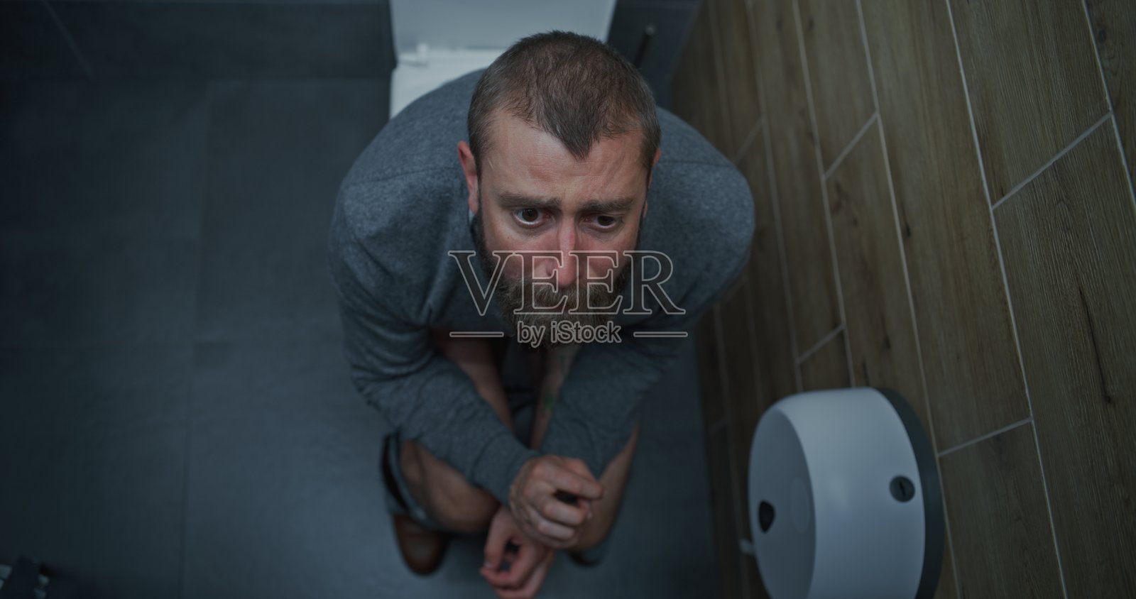 腹泻和消化不良导致表情紧张的商界男士坐在马桶上照片摄影图片