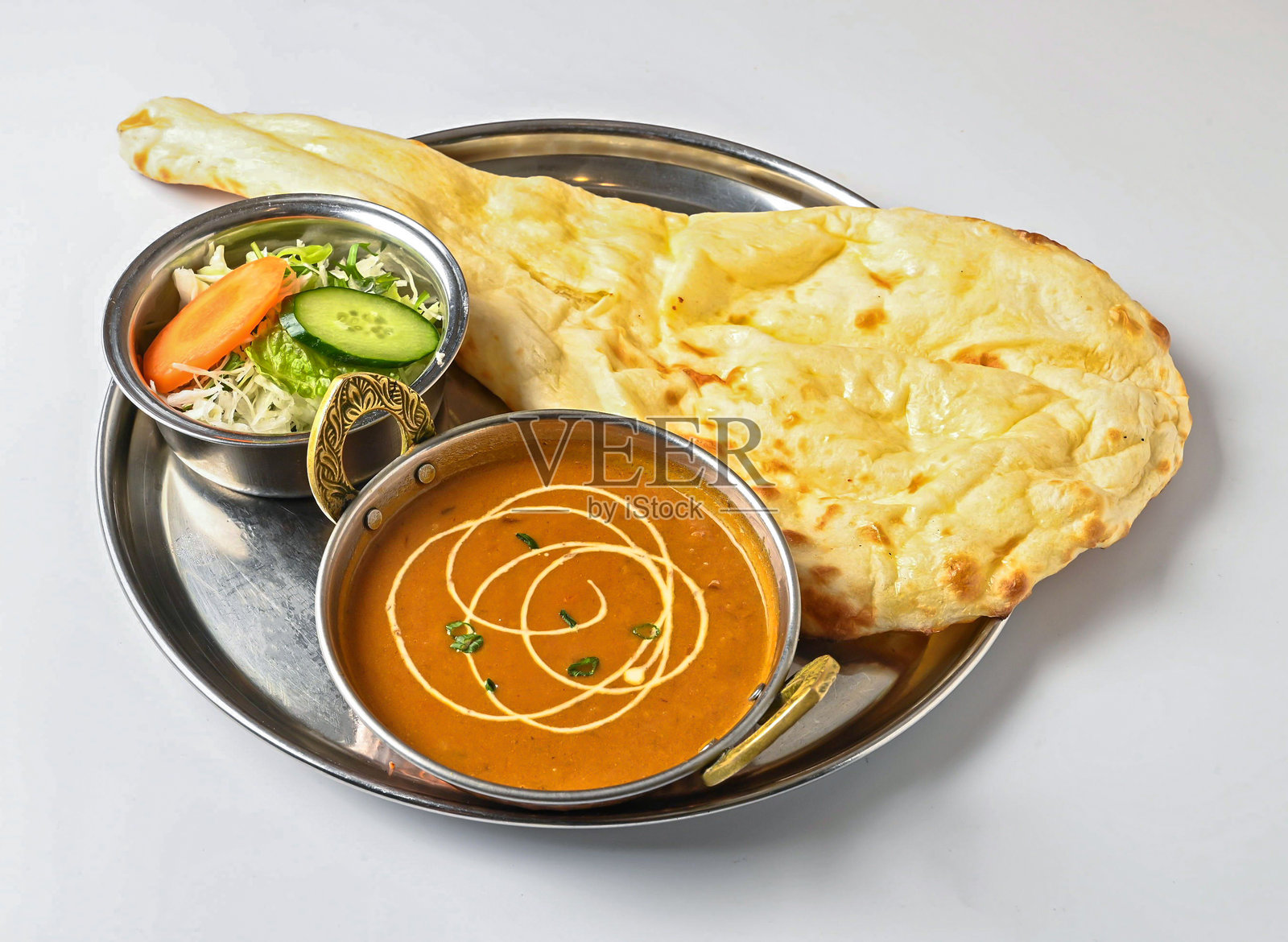 金属餐盘里的美味印度套餐，包含印度烤饼、玛卡尼扁豆和沙拉，白色背景，印度菜肴侧视图照片摄影图片