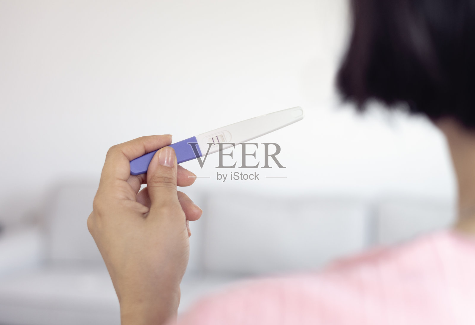 一名女性手持显示阳性结果的验孕棒。特写镜头展示一位怀孕的女性，展现母性与孕期检查。照片摄影图片