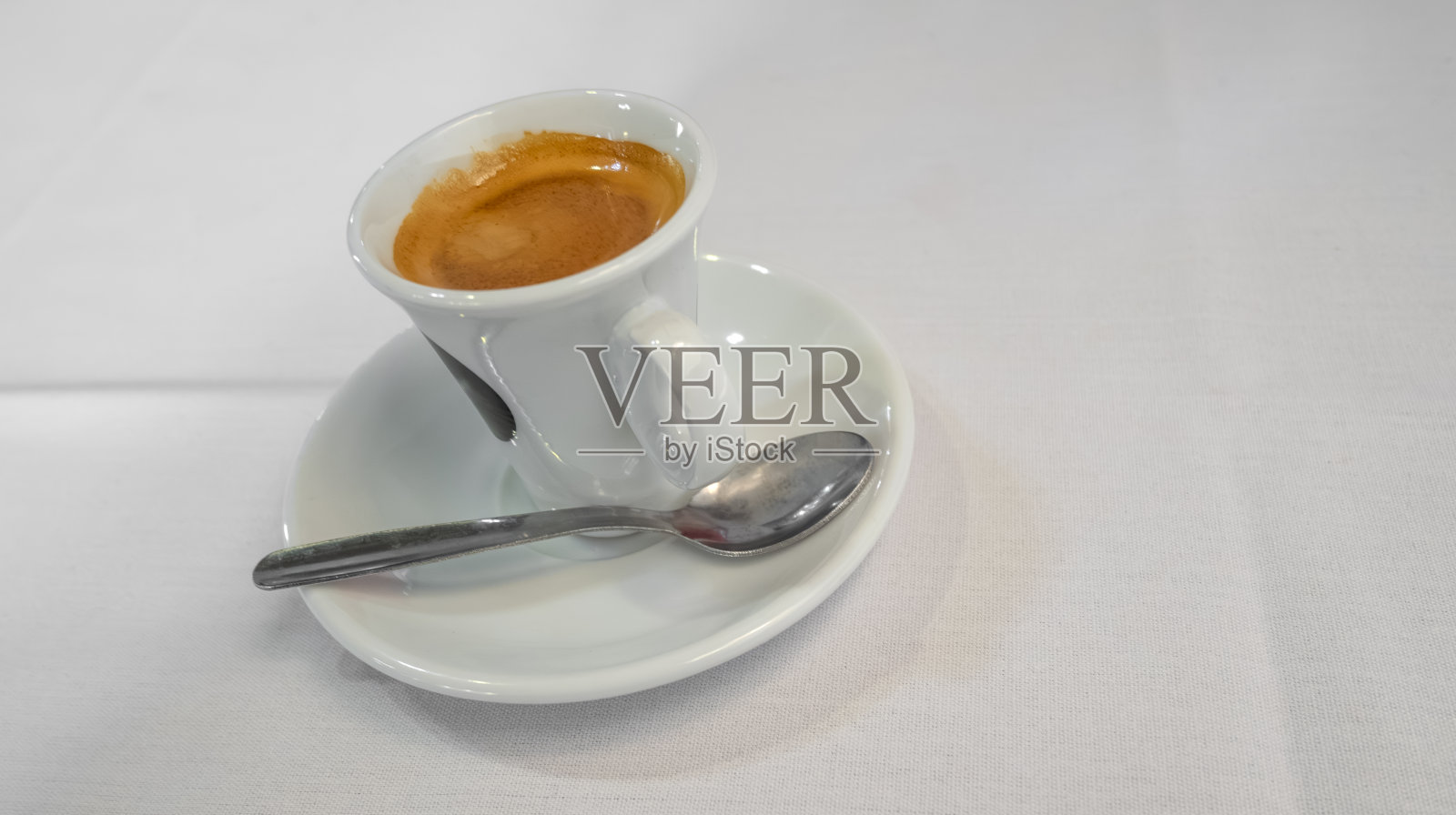 白色背景下的咖啡杯、碟子和勺子照片摄影图片