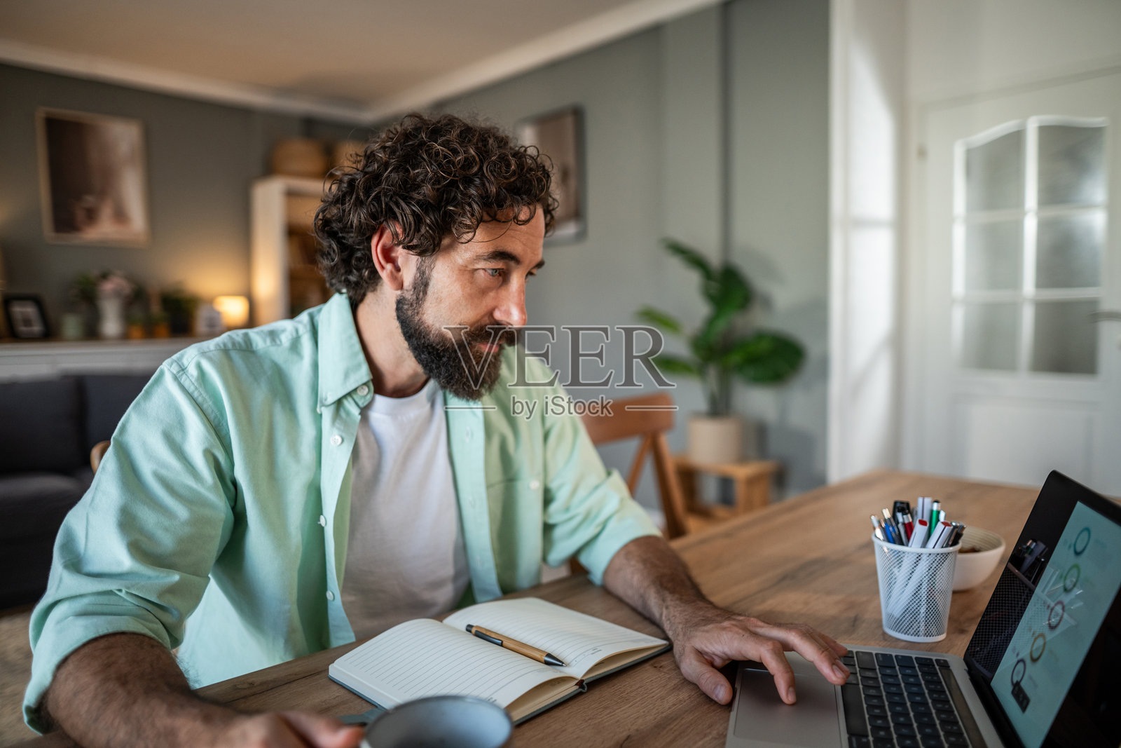 居家办公室里，一名男子在家通过笔记本电脑远程工作。照片摄影图片