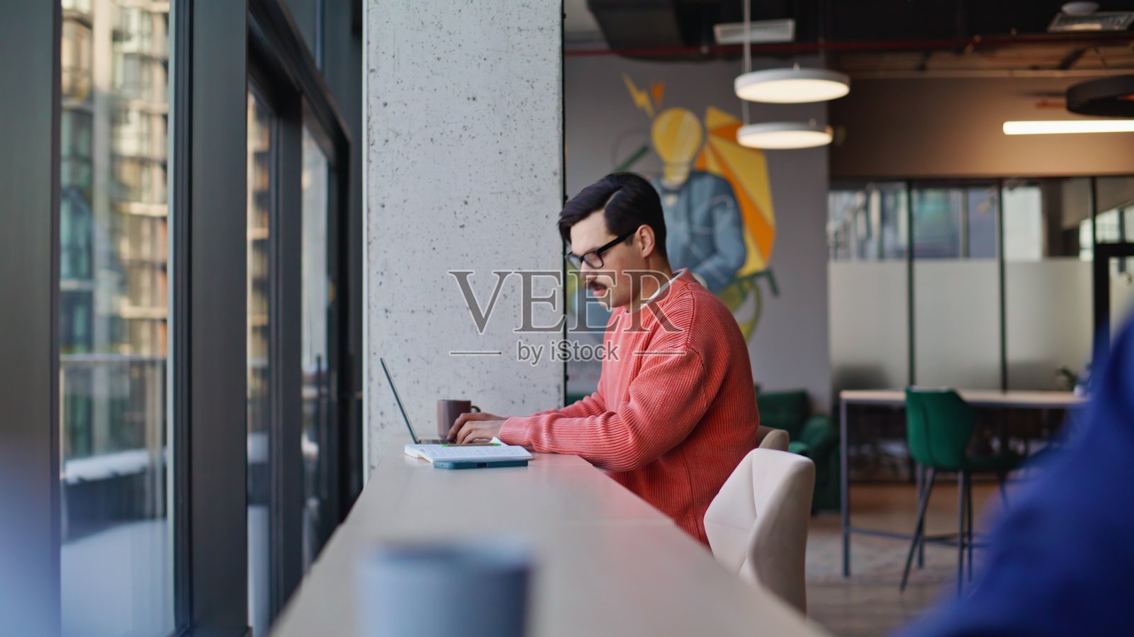 两名学生在咖啡馆空间使用笔记本电脑工作。一名专注的男子正在打字。照片摄影图片