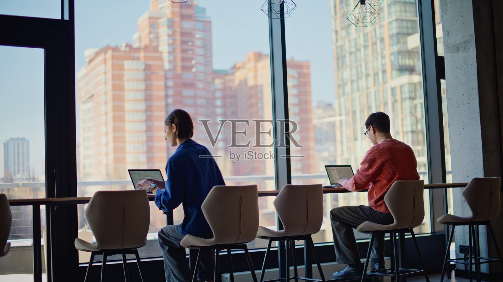 同事们在现代工作空间里忙于在线工作。两位自由职业者使用笔记本电脑。照片摄影图片