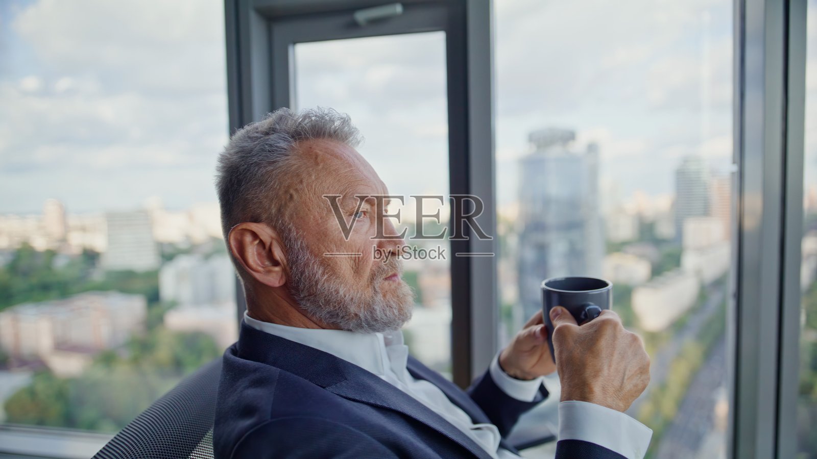 智能企业家在全景窗前的办公室里喝咖啡，特写照片摄影图片