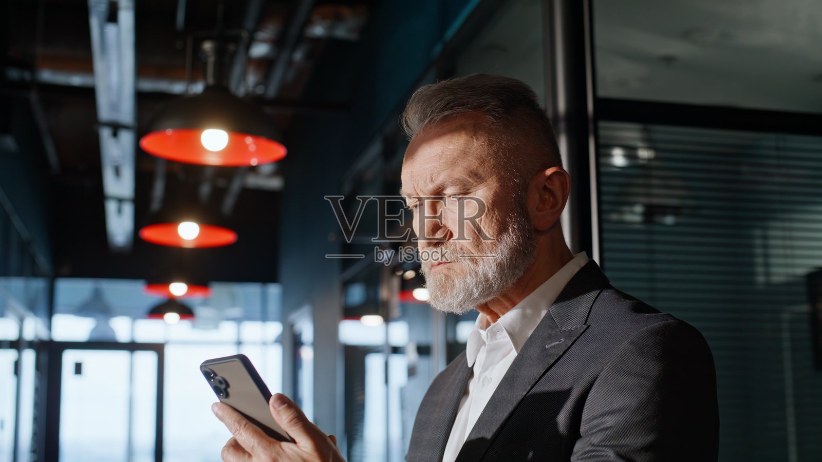 特写镜头：一位年长的企业家在办公楼走廊里看手机。照片摄影图片
