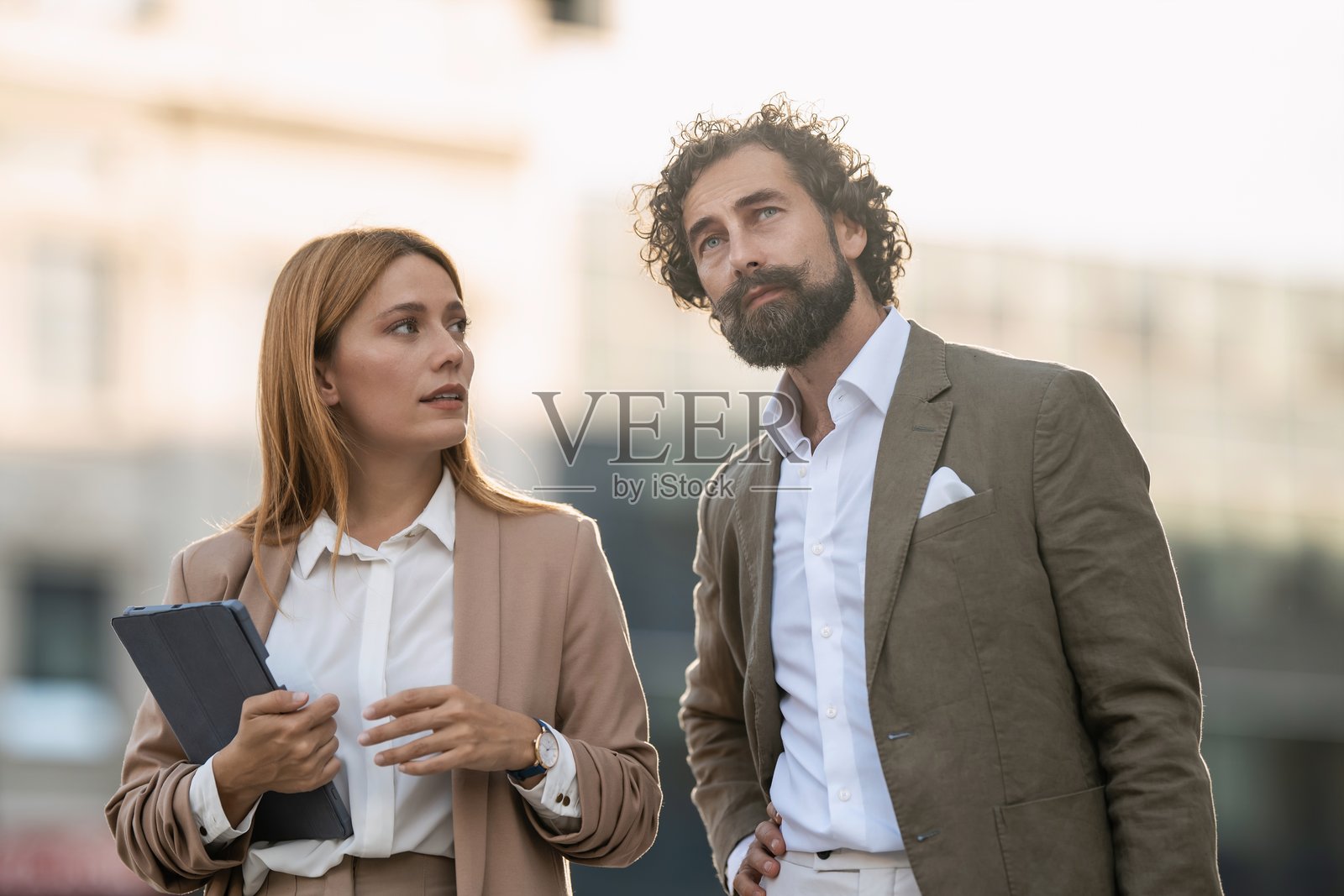 商务人士在城市环境中讨论项目，手中拿着平板电脑照片摄影图片