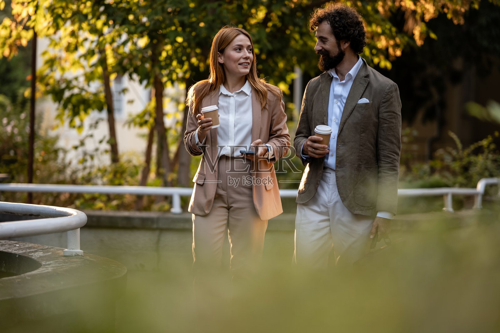 商务人士在户外咖啡休息时间边走边谈照片摄影图片