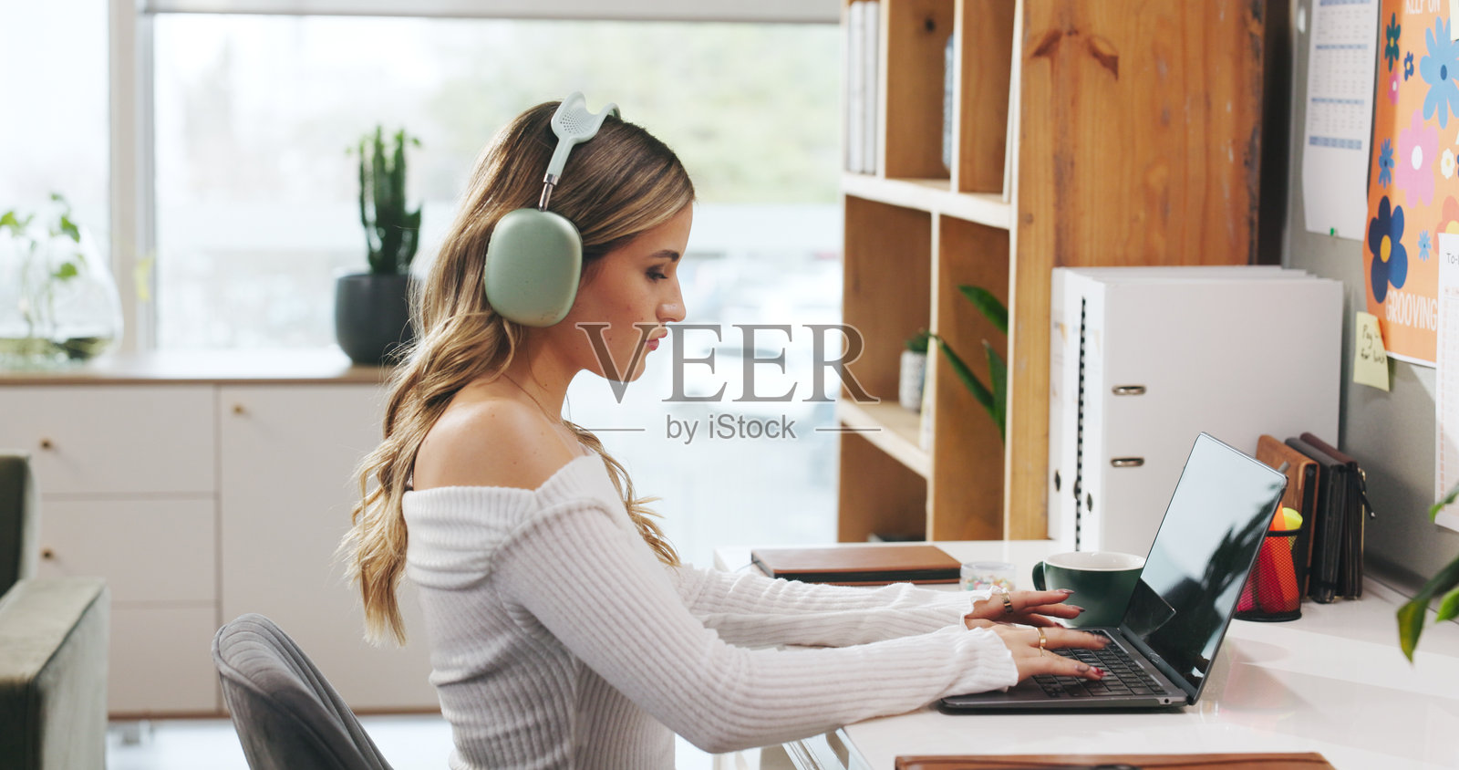 家庭办公室，戴着耳机打字的女人，用于在线工作、撰写博客或编辑。自由职业，技术，以及在书桌前进行内容创作、写作或播客搜索的人。照片摄影图片