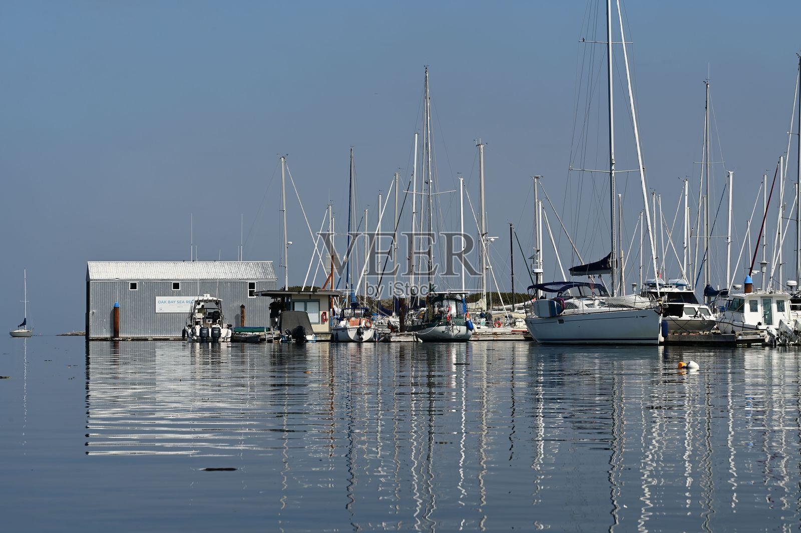 宁静的码头，帆船和船屋倒映其中。照片摄影图片