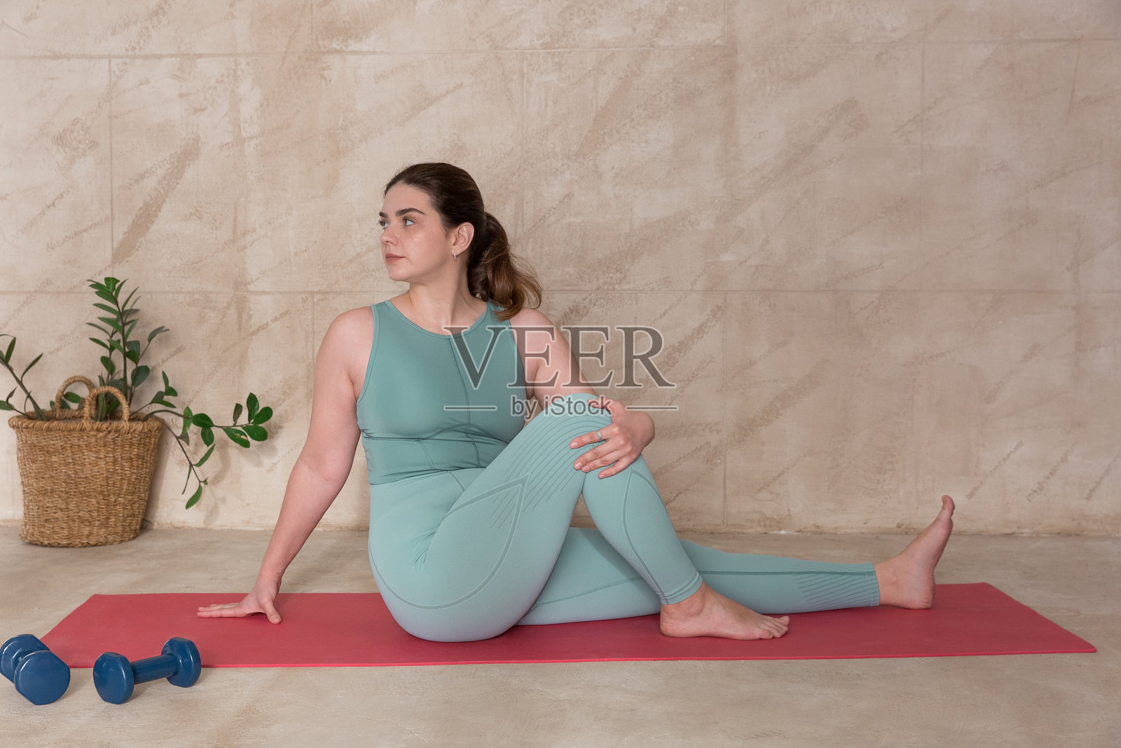 年轻女子身着运动服在家中瑜伽垫上做伸展运动照片摄影图片