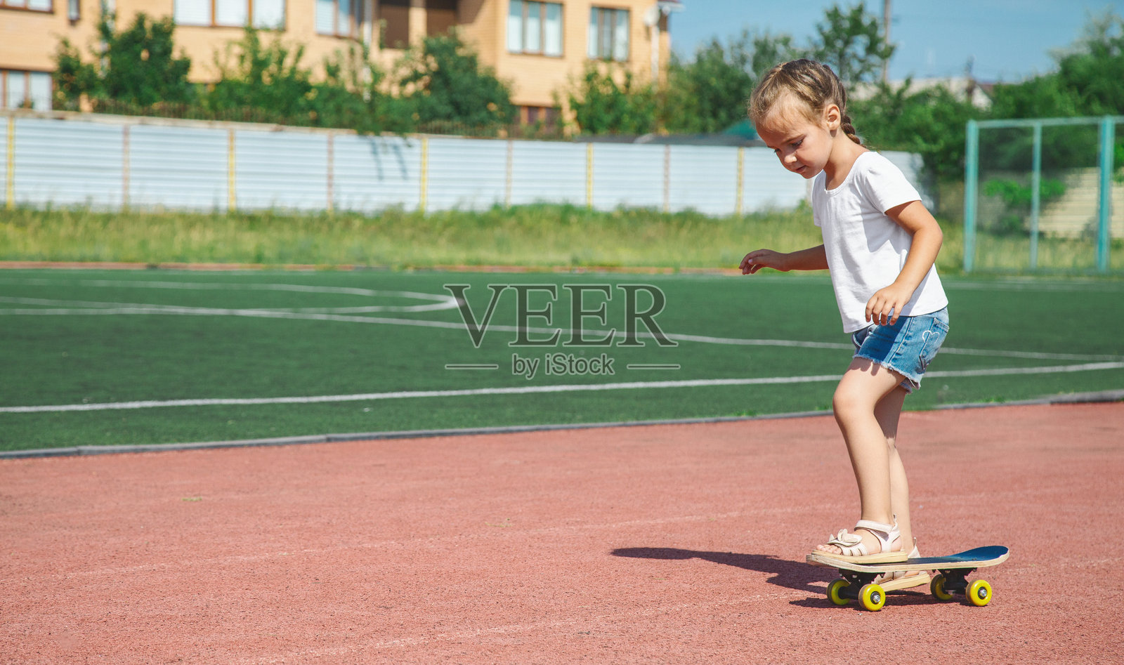 快乐微笑的小女孩在玩滑板时保持平衡照片摄影图片