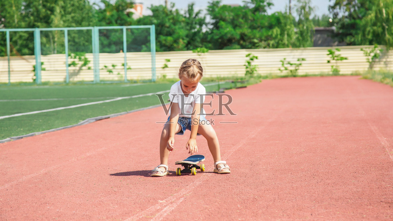 快乐微笑的女孩在玩滑板时保持平衡照片摄影图片