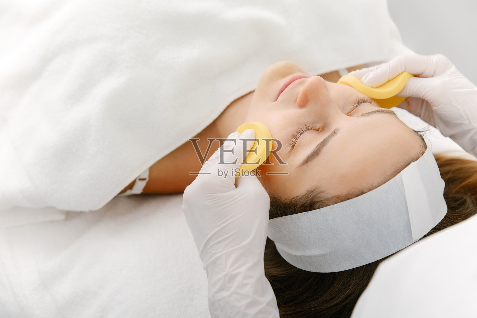 美容师在水疗中心为顾客敷脸部护理贴片，享受放松的脸部护理照片摄影图片