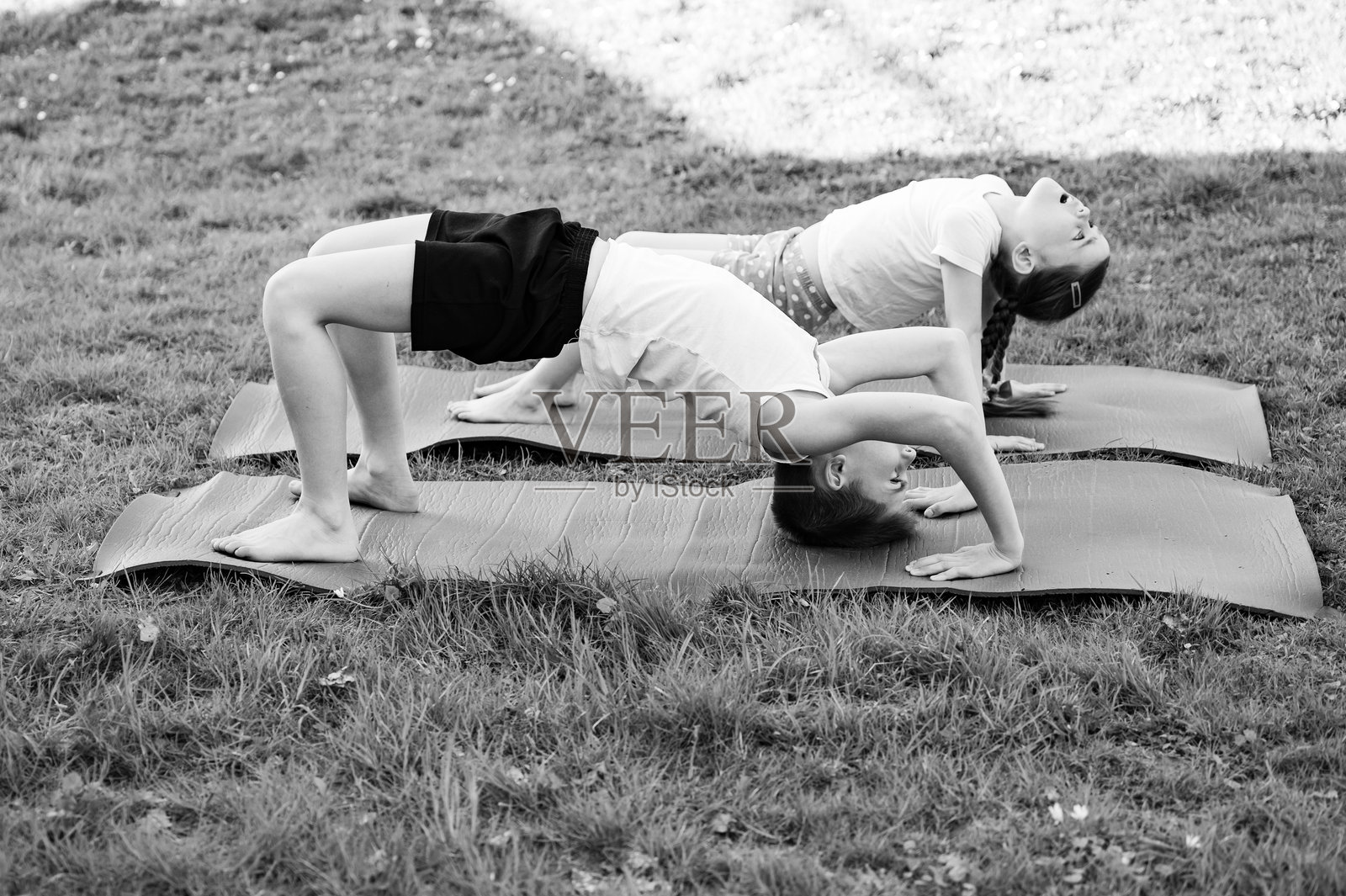 孩子们在垫子上练习瑜伽，展现健康积极的生活方式。照片摄影图片