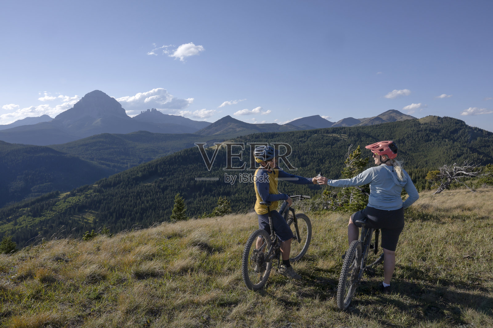 成熟夫妇在山间草地上享受电动自行车的悠闲时光照片摄影图片