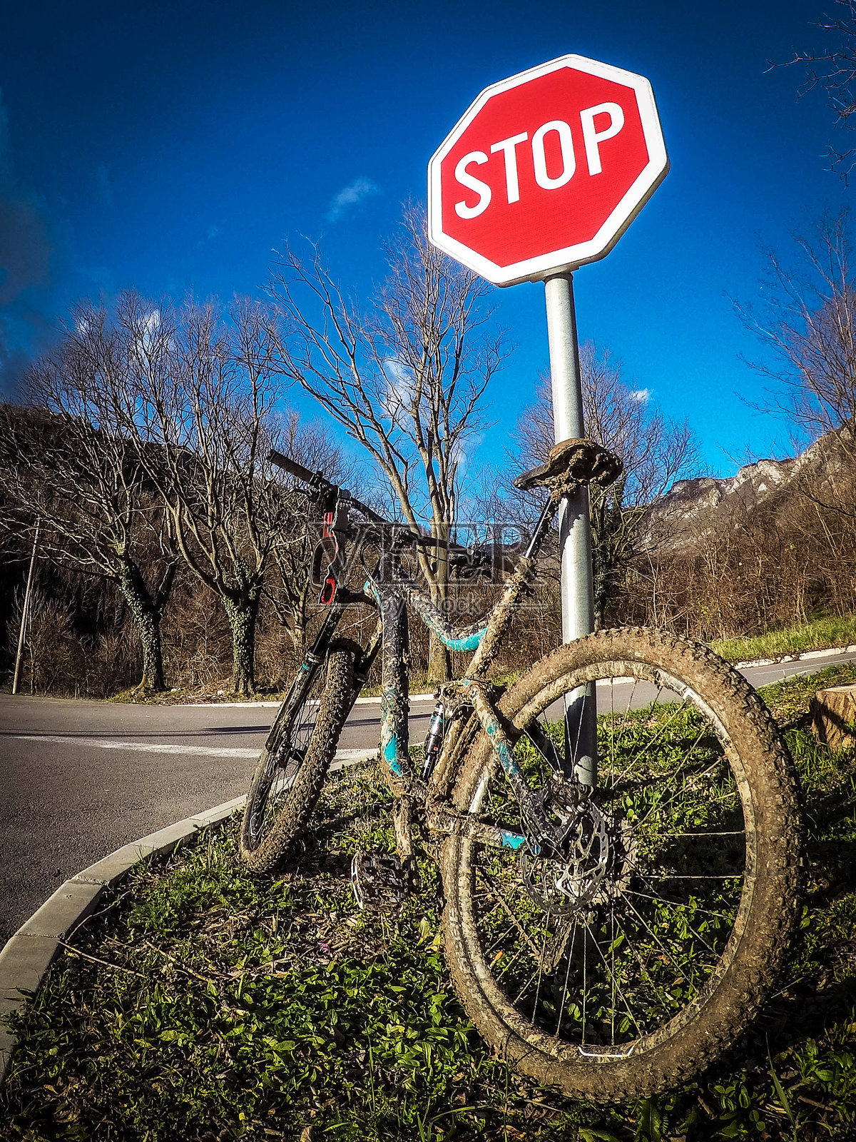 骑行后停在停车标志旁的泥泞下坡自行车照片摄影图片