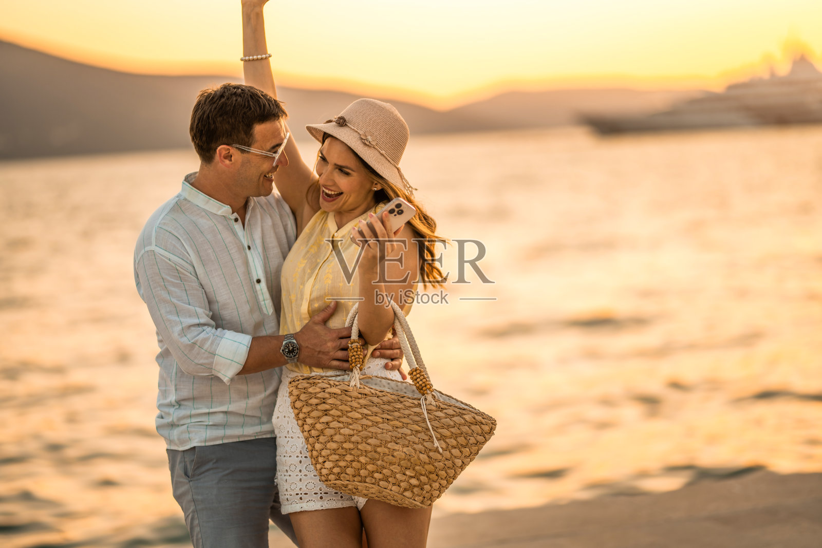 情侣在夏日海滨度假，在海边拥抱嬉戏。照片摄影图片