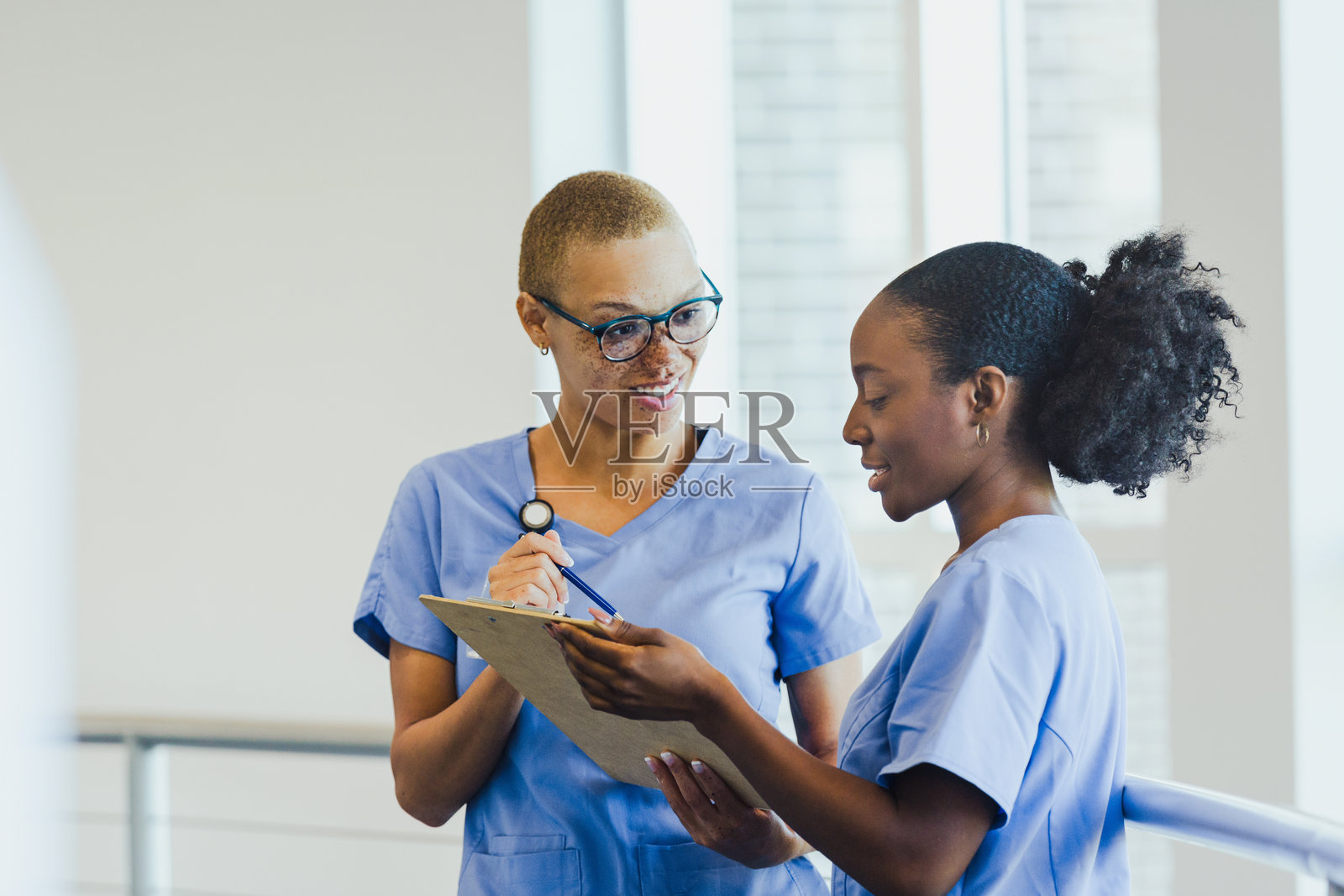 两位护士在明亮的医疗机构中协作审阅病人病历。照片摄影图片