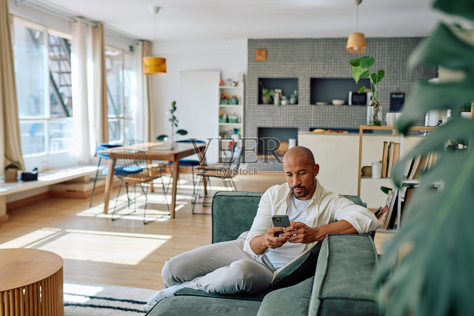 男人在现代公寓的沙发上放松地使用智能手机照片摄影图片