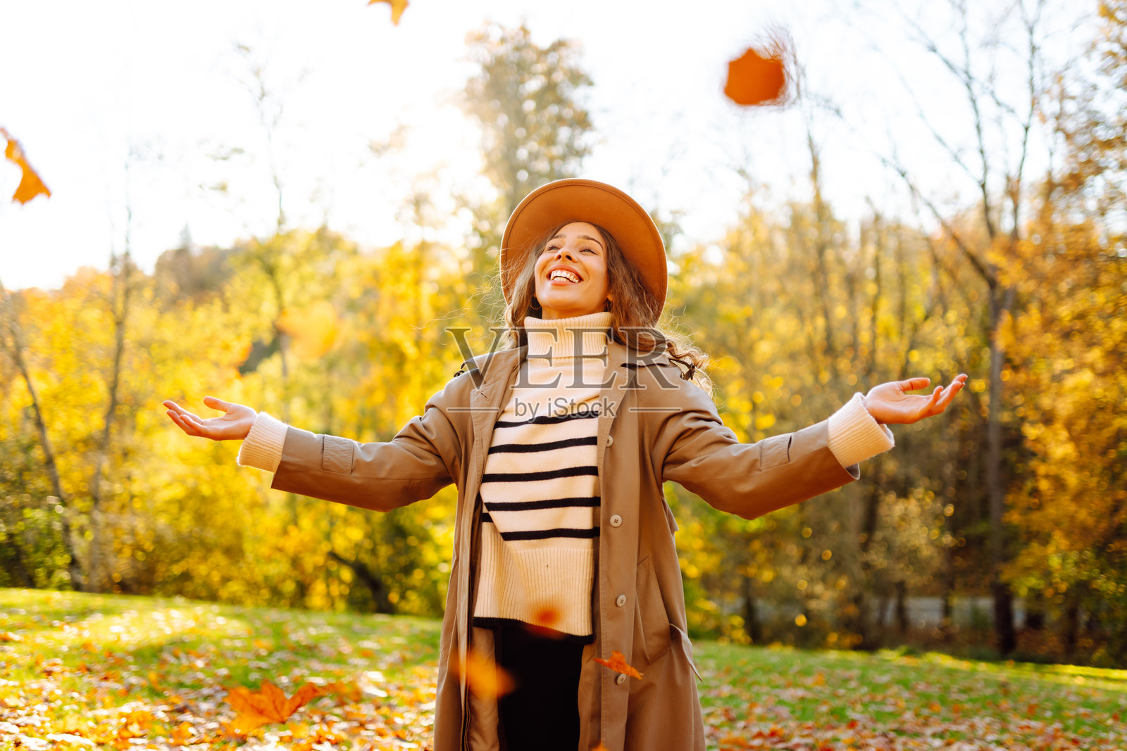 日落时分，一位快乐的女士在秋季公园里玩耍。照片摄影图片