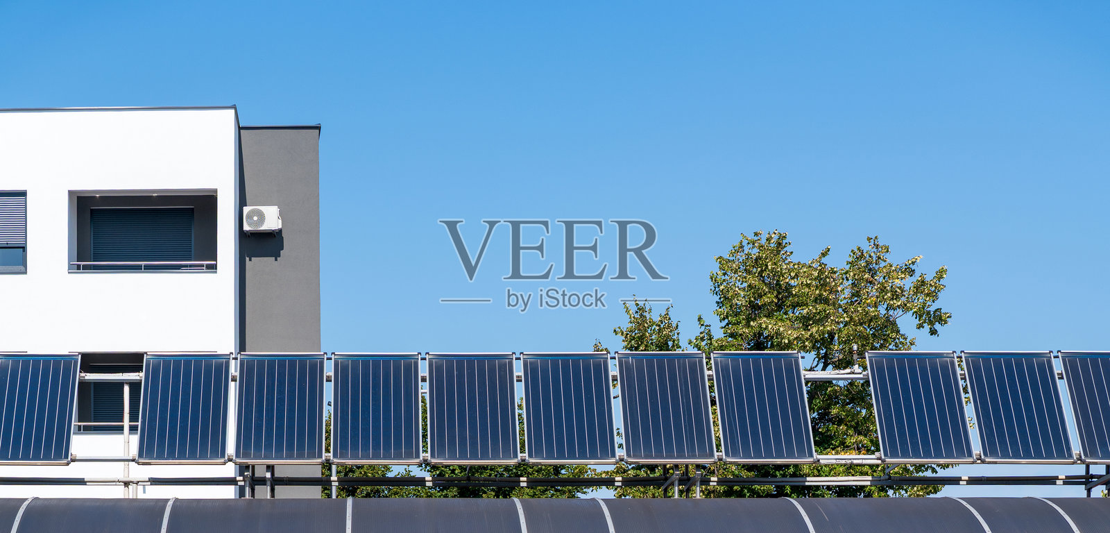 城市住宅楼前一排太阳能电池板。照片摄影图片