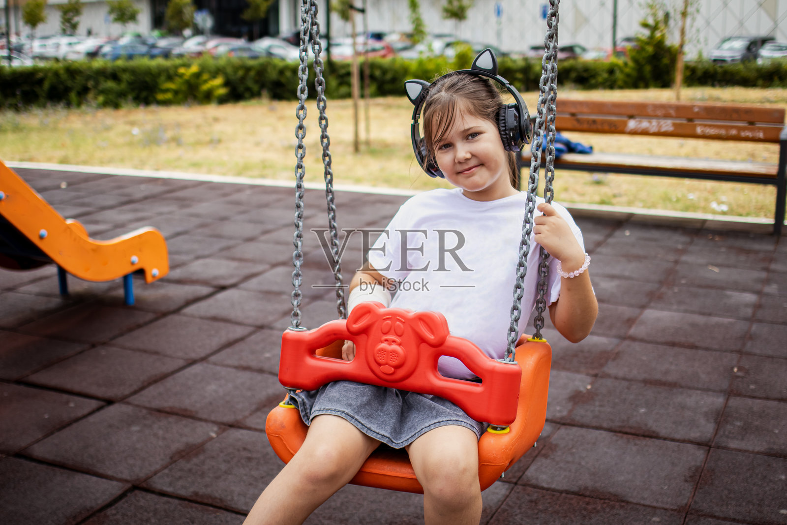 一个顽皮、快乐的小女孩在公共公园里玩耍，她的一只胳膊打着石膏。照片摄影图片