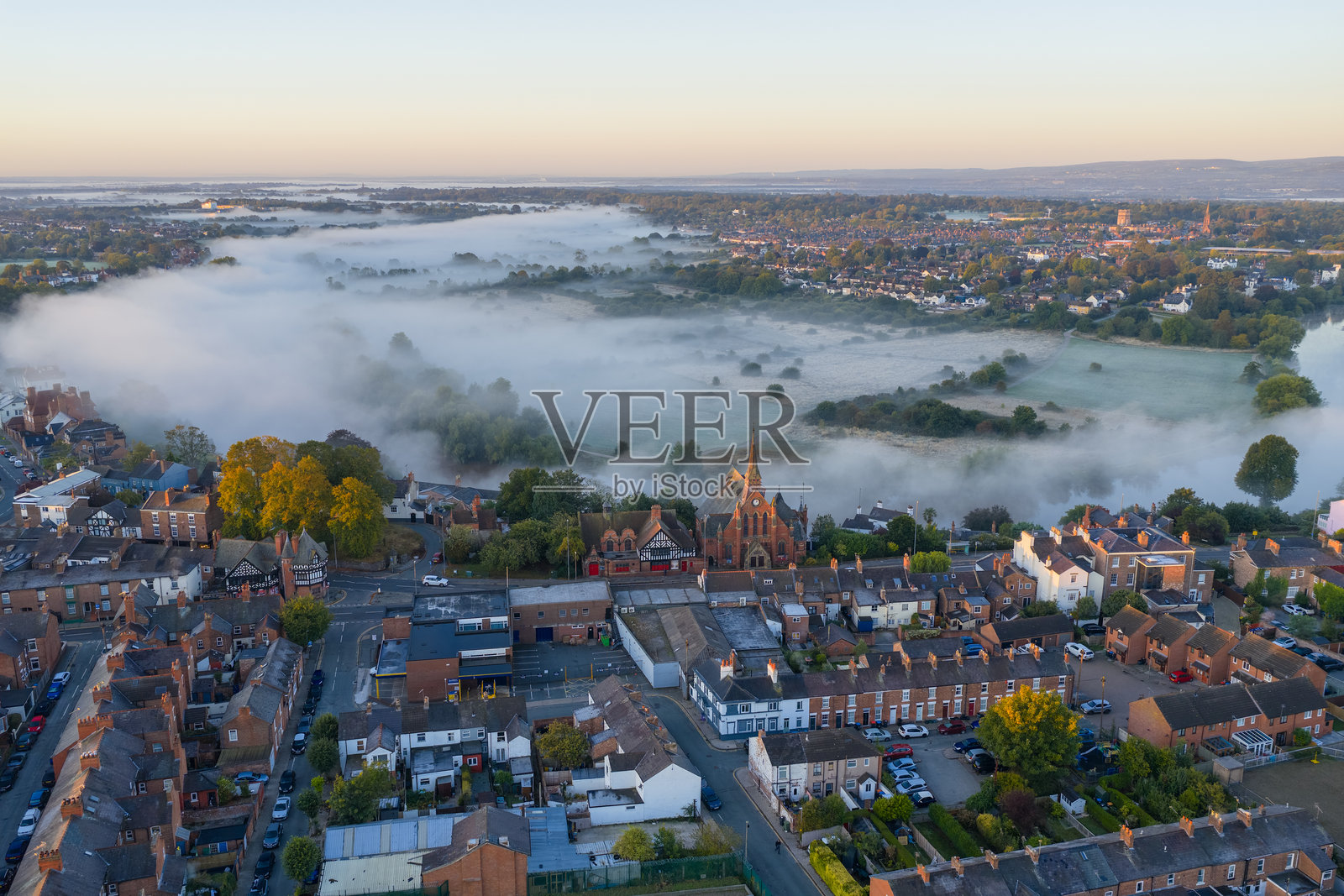 日出时分，切斯特的晨雾笼罩着屋顶、教堂尖塔和周围的田野。照片摄影图片