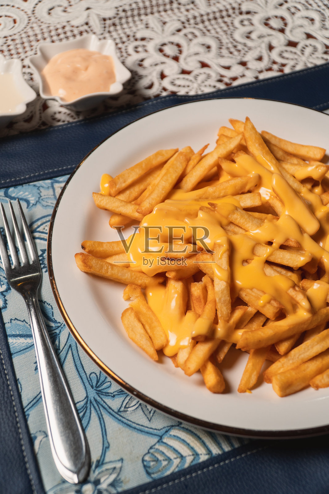 盘子里放着融化奶酪的法式炸薯条特写。照片摄影图片