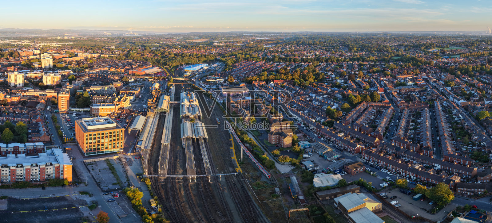 日出时分切斯特火车站的宽幅全景，包含火车、轨道和周围的屋顶。照片摄影图片