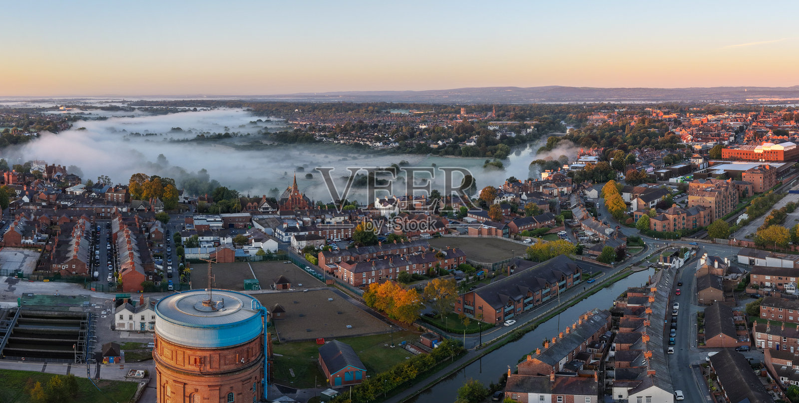 日出时切斯特的全景航拍，薄雾笼罩着田野和屋顶。照片摄影图片