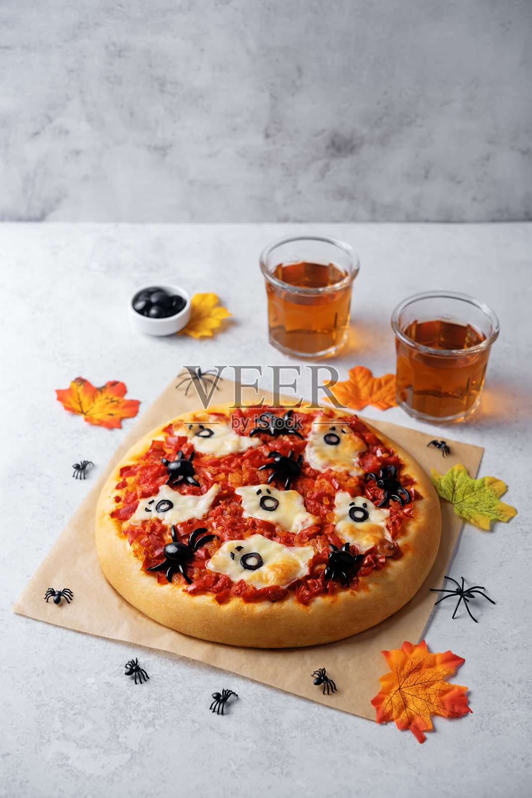 为万圣节制作的玛格丽特披萨，上面装饰着蜘蛛形状的黑橄榄和鬼魂形状的马苏里拉奶酪照片摄影图片